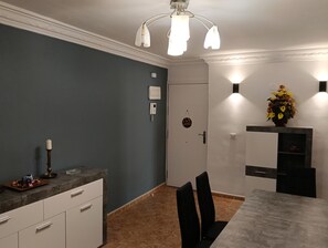 Eine moderne Küche mit dunkelblauer Wand, weißen Schränken, einer Marmorarbeitsplatte und einem Essbereich mit Tisch und Stühlen.