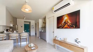 Un espacio moderno de estar con comedor, una mesa de centro y un cuadro de un fuego.