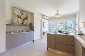 Una cocina moderna con un amplio ventanal, una lámpara colgante y una planta decorativa.