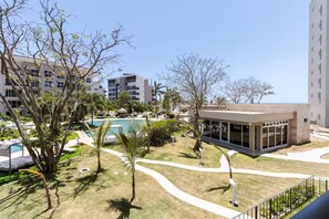 A modern hotel with a swimming pool, palm trees, and a view of other buildings. - Exclusivo apartamento con vista a la piscina (punta chame)