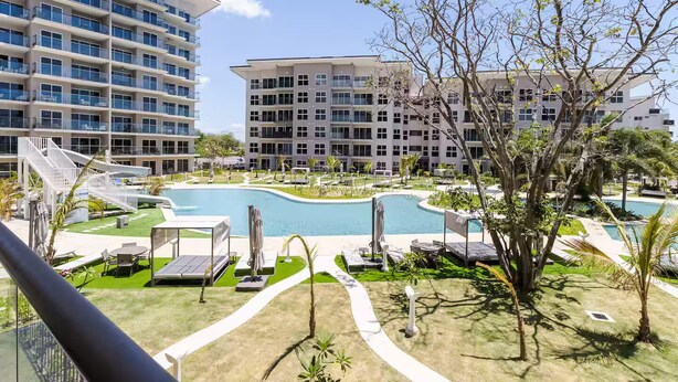 Un hotel con piscina, mobiliario exterior y vistas a otros edificios.