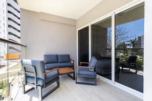 A balcony with a sofa, two armchairs, and a small wooden table. - Exclusivo apartamento con vista a la piscina (punta chame)