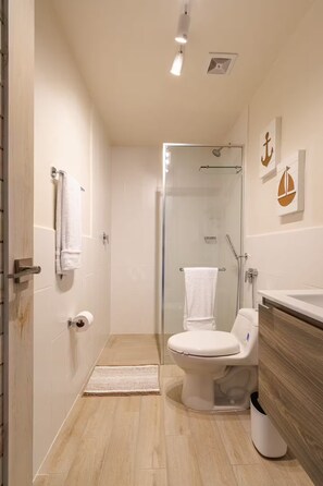 Une salle de bain moderne avec une douche à parois de verre, des toilettes et un lavabo.
