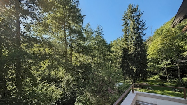A balcony with a view of a lush garden and tall trees. - Wald Villa Üssbach- Your paradise between Cochem and Zell at the Moselle (Alf)