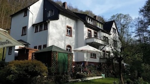 A large, multi-story building with a white facade and dark roof, surrounded by a well-maintained garden with outdoor seating. - Wald Villa Üssbach- Your paradise between Cochem and Zell at the Moselle (Alf)