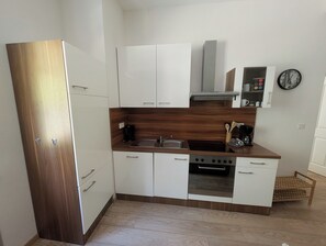 A compact kitchen with white cabinets, a wooden countertop, a stove, and a sink. - Wald Villa Üssbach- Your paradise between Cochem and Zell at the Moselle (Alf)