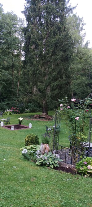 A garden with a wooden bench, a table, and chairs. - Wald Villa Üssbach- Your paradise between Cochem and Zell at the Moselle (Alf)