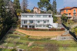 Una casa moderna de dos pisos con techo plano, ventanas amplias y un balcón.