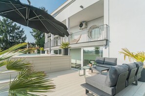 A modern outdoor living area with a sofa, a table, and an umbrella.