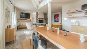 Una sala de estar moderna con una mesa de comedor de madera, asientos cómodos, un televisor y una chimenea.