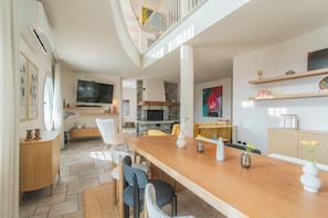Un salon moderne avec une table à manger en bois, des sièges confortables, un téléviseur et une cheminée.