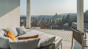 Un balcón con vista a la ciudad, un sofá con cojines y una silla.
