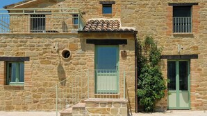Ein Steinhaus mit grüner Tür, einem kleinen Balkon und einem Fenster.