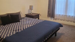 A bedroom with a large bed, a nightstand, a lamp, and a window with curtains. - Relax & unwind in a spacious 3-bedroom townhouse with 4 beds in Barefoot Resorts (North Myrtle Beach)