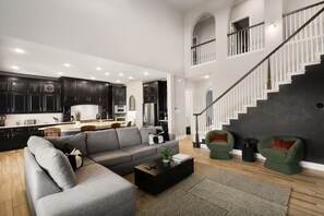 Ein modernes Wohnzimmer mit einer Eckcouch, einem Couchtisch und einer Treppe.