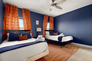 Une chambre d’hôtel avec deux lits, un ventilateur de plafond et une vue sur le ciel par la fenêtre.
