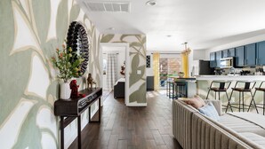 Una cocina moderna con armarios oscuros, una isla central y una zona de comedor con taburetes de bar.