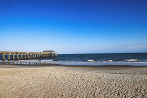 Una spiaggia con un molo che si protende verso l'oceano.