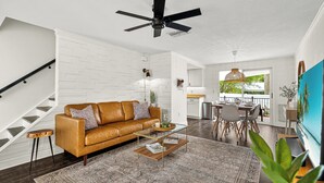 A modern living room with a brown leather sofa, a glass coffee table, and a patterned rug. - Mins to Beaches/Downtown, Quiet Neighborhood, Community Pool (Sarasota)