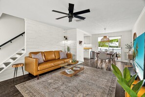A modern living room with a brown leather sofa, a glass coffee table, and a patterned rug. - Mins to Beaches/Downtown, Quiet Neighborhood, Community Pool (Sarasota)