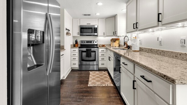 A modern kitchen with stainless steel appliances, white cabinetry, and a granite countertop. - Mins to Beaches/Downtown, Quiet Neighborhood, Community Pool (Sarasota)