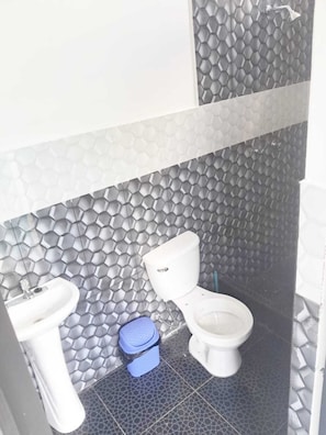 Ein Badezimmer mit Toilette, Waschbecken und einer blauen Mülleimer.