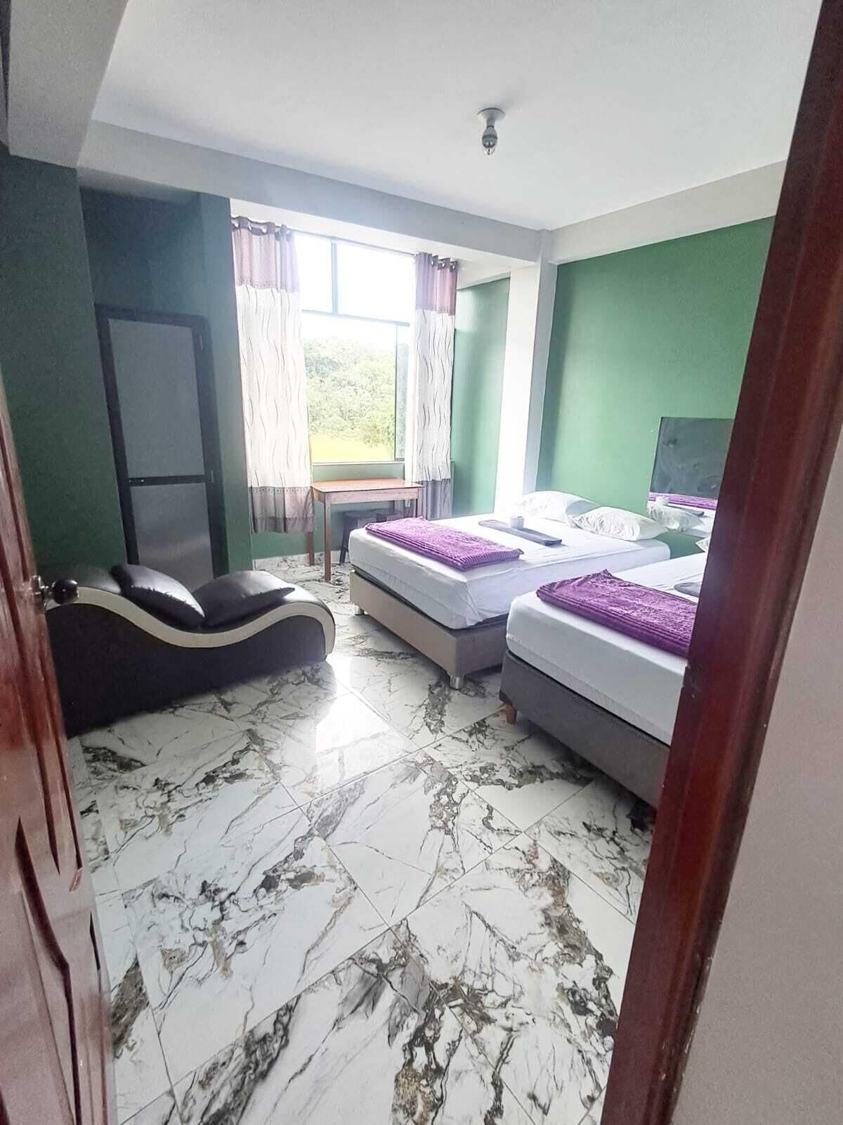 A room with two beds, a desk, a chair, and a television.