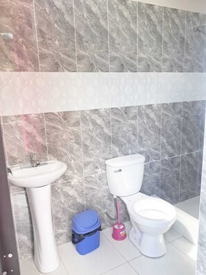 A bathroom with a sink, toilet, bidet, and a blue trash bin. - Hospedaje punto de encuentro (Moyobamba)