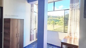 Una habitación con un ventanal grande, una mesa de madera, una silla y un armario.