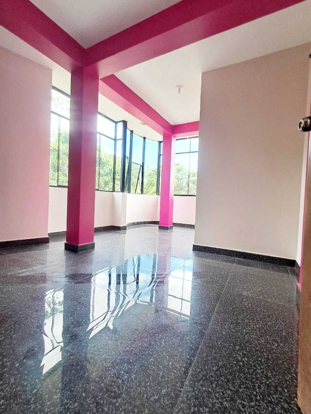 A spacious room with large windows, a polished floor, and pink structural elements.