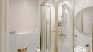Ein modernes Badezimmer mit einer begehbaren Glasdusche, einem Standwaschbecken und einem Spiegel.