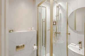 Ein modernes Badezimmer mit einer begehbaren Glasdusche, einem Standwaschbecken und einem Spiegel.
