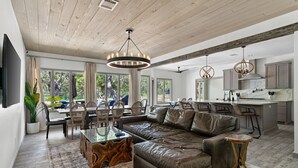 Una sala de estar moderna con un sofá de cuero en forma de L, una mesa de centro de vidrio y un comedor con sillas de madera.