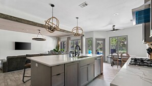 Una cocina moderna con una isla central, electrodomésticos integrados y ventanas amplias.