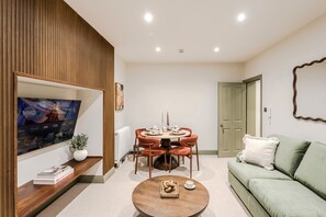 Ein Wohnzimmer mit Fernseher, einem Esstisch mit Stühlen, einer Couch und einem Couchtisch.