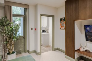 Ein Flur mit Blumentopf, einer Tür zu einem Badezimmer, einer Wand aus Holzpaneelen und einem Regal mit Dekoration.