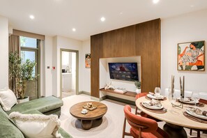 Ein modernes Wohnzimmer mit Fernseher, Sitzgelegenheiten und Essbereich.