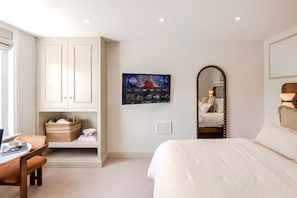 A bedroom with a bed, a desk with a chair, a television mounted on the wall, and a large mirror. - Your Apartment - Earl's Court | Studio - Top floor (London)