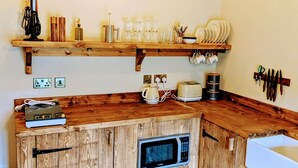 A kitchen with wooden cabinets, a microwave, a coffee maker, and various kitchen utensils. - 8 Henham Barns, Henham Park, Nr Southwold, Suffolk (Suffolk)