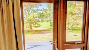 A wooden-framed door with a view of a grassy area and trees. - 8 Henham Barns, Henham Park, Nr Southwold, Suffolk (Suffolk)