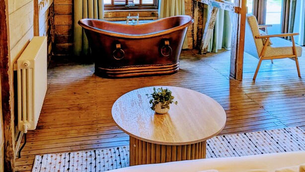A rustic wooden room with a large bathtub, a wooden chair, and a round table with a plant. - 8 Henham Barns, Henham Park, Nr Southwold, Suffolk (Suffolk)