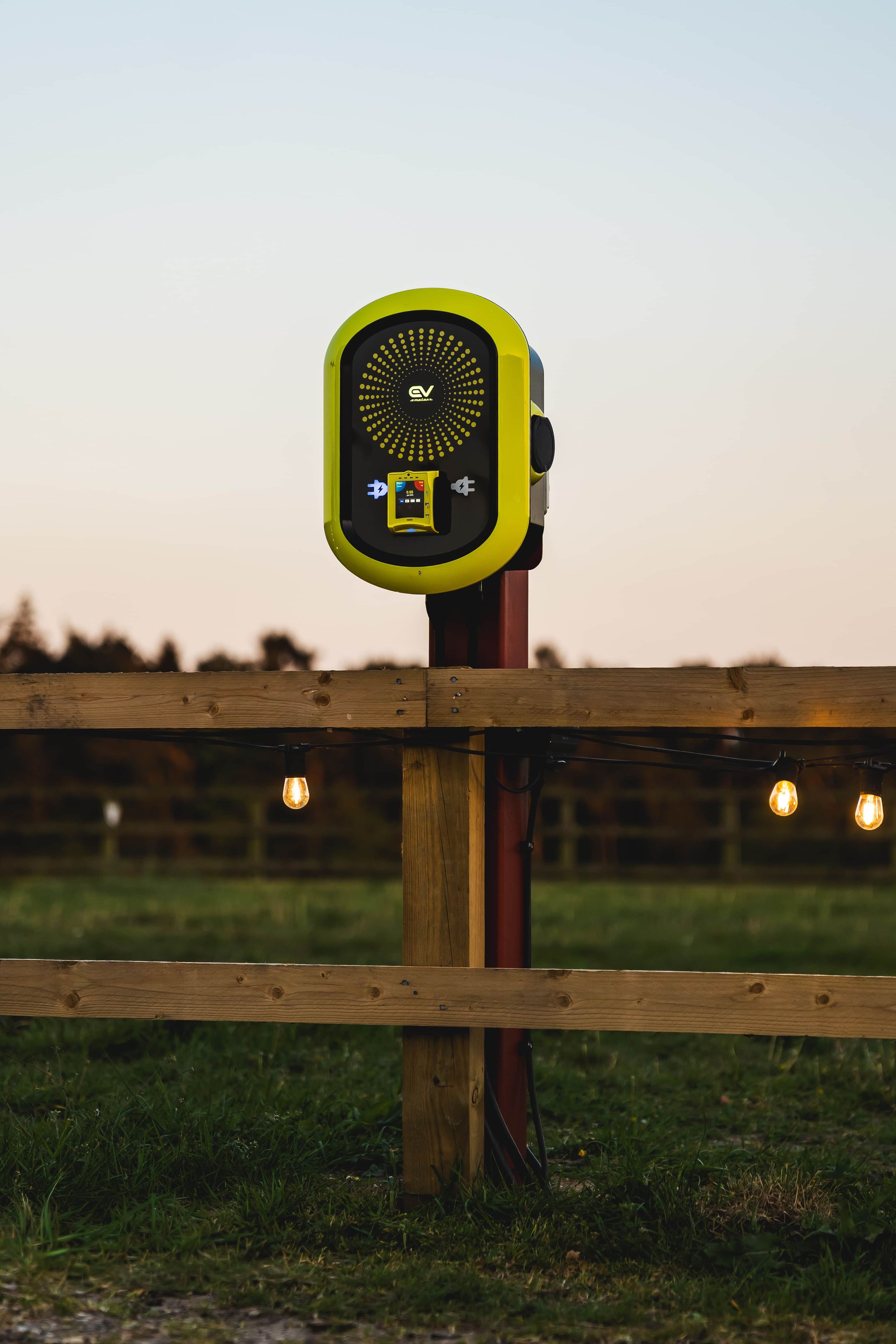 A device mounted on a wooden post with a grassy field in the background.