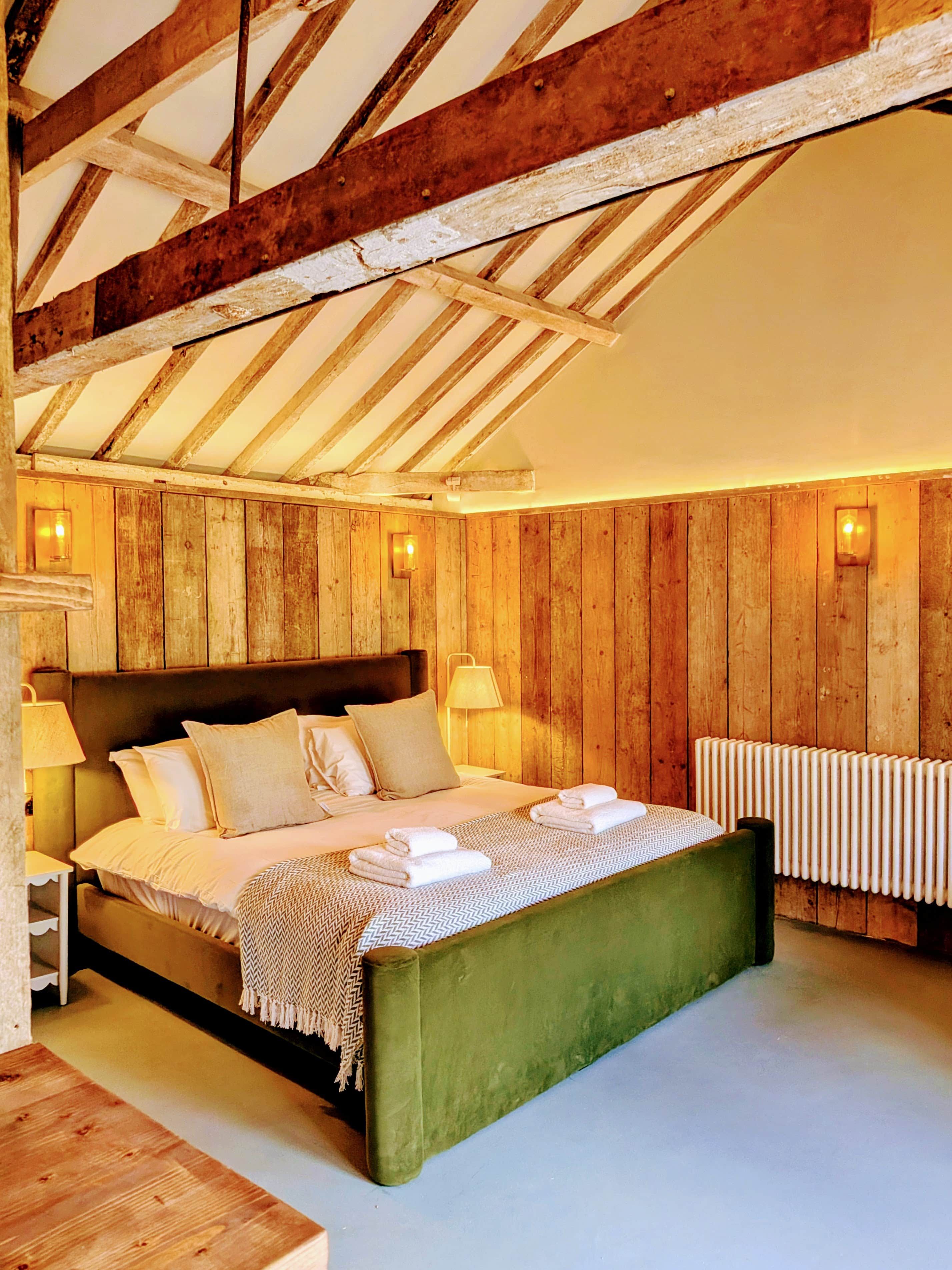 Ein Schlafzimmer mit Holzboden, einem grünen Bett, weißer Bettwäsche und einer Heizung.