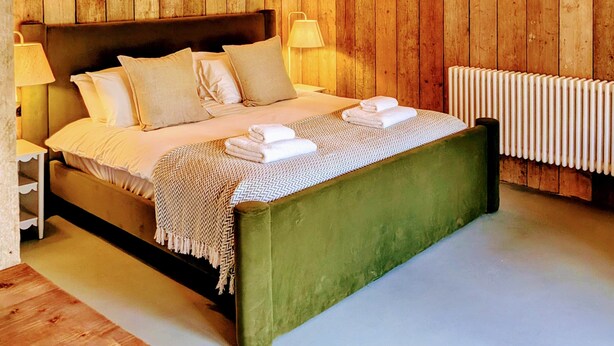 A bedroom with a wooden ceiling, a green bed, white bedding, and a radiator. - 6 Henham Barns, Henham Park, Nr Southwold, Suffolk (Suffolk)