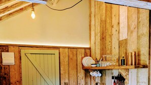 A rustic kitchen with wooden walls, a wooden countertop, a sink, and a door leading to another room. - 6 Henham Barns, Henham Park, Nr Southwold, Suffolk (Suffolk)
