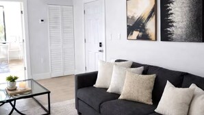 A living room with a dark sofa, a glass coffee table, and two abstract paintings on the wall. - Miami Luxury 2BR, FIFA Ready, Brickell (Miami)