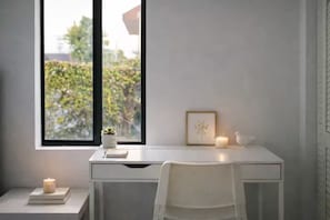 Habitación minimalista con escritorio, silla y ventana con vistas a la vegetación.