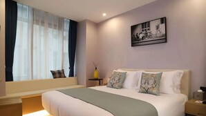 A hotel room with a large bed, a bedside table, a small table with a vase, a window with curtains, and a painting on the wall. - Yooli Hotel shanghai (Shanghai)