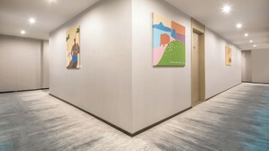A hallway with white walls, a wooden door, and artwork on the walls. - Yooli Hotel shanghai (Shanghai)