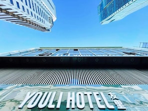 The exterior of the YOLI HOTEL with a modern architectural design, featuring a prominent sign and a clear view of the surrounding buildings. - Yooli Hotel shanghai (Shanghai)